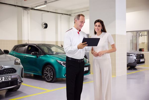 Elindeki Toyota Corolla kullanıcı el kitabını inceleyen takım elbiseli oturan bir adam