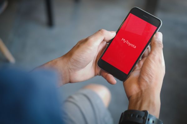 Eine Hand hält ein Smartphone mit der Seite MyToyota App.